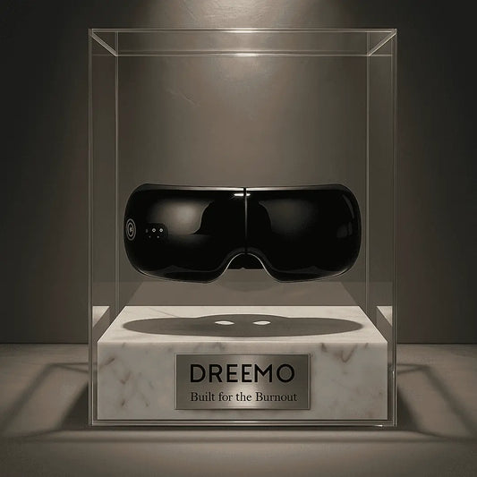 Dreemo Elixir One™ Eye Massager in black displayed in a luxury glass case with 'Built for the Burnout' plaque, ideal for migraine and eye strain relief.